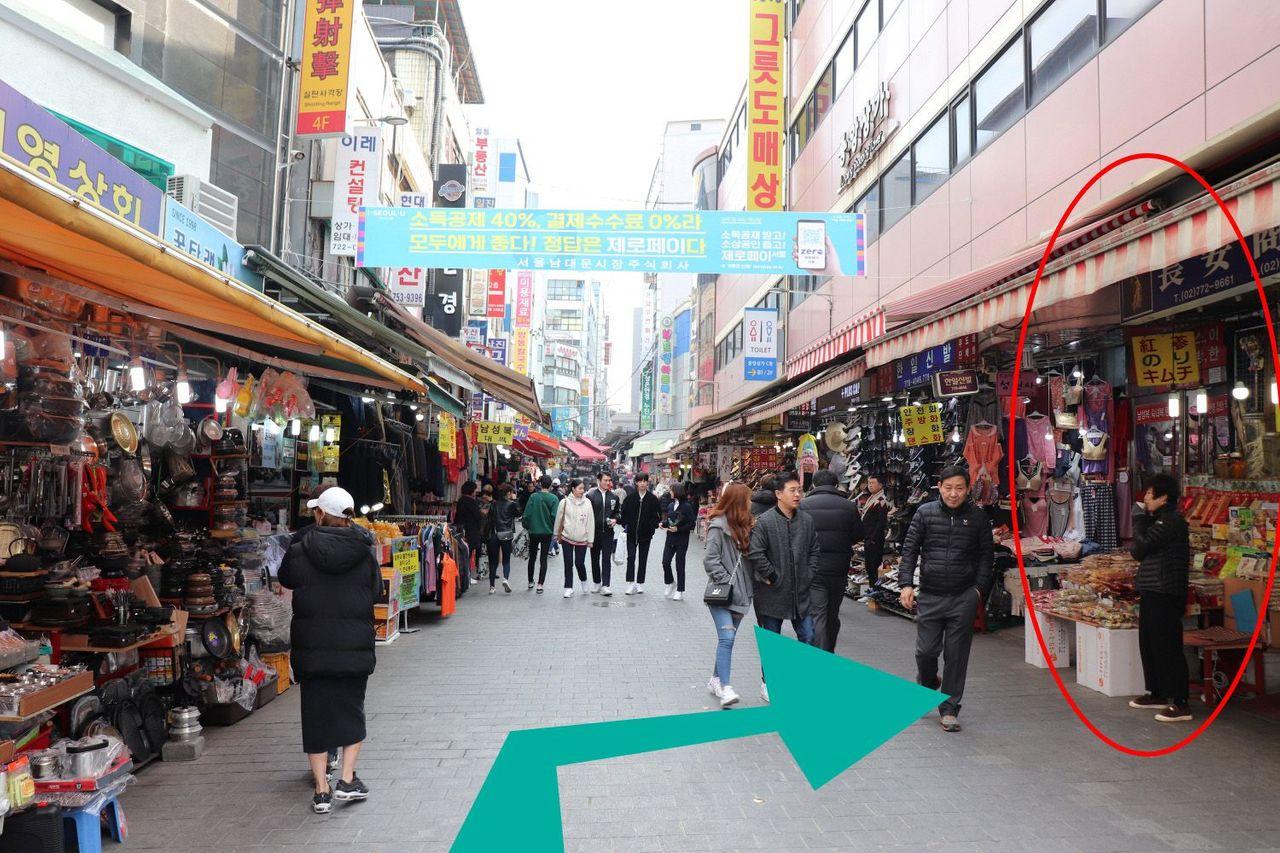 Shoppers in Namdaemun Market with store signs and directions to Jangan Store.